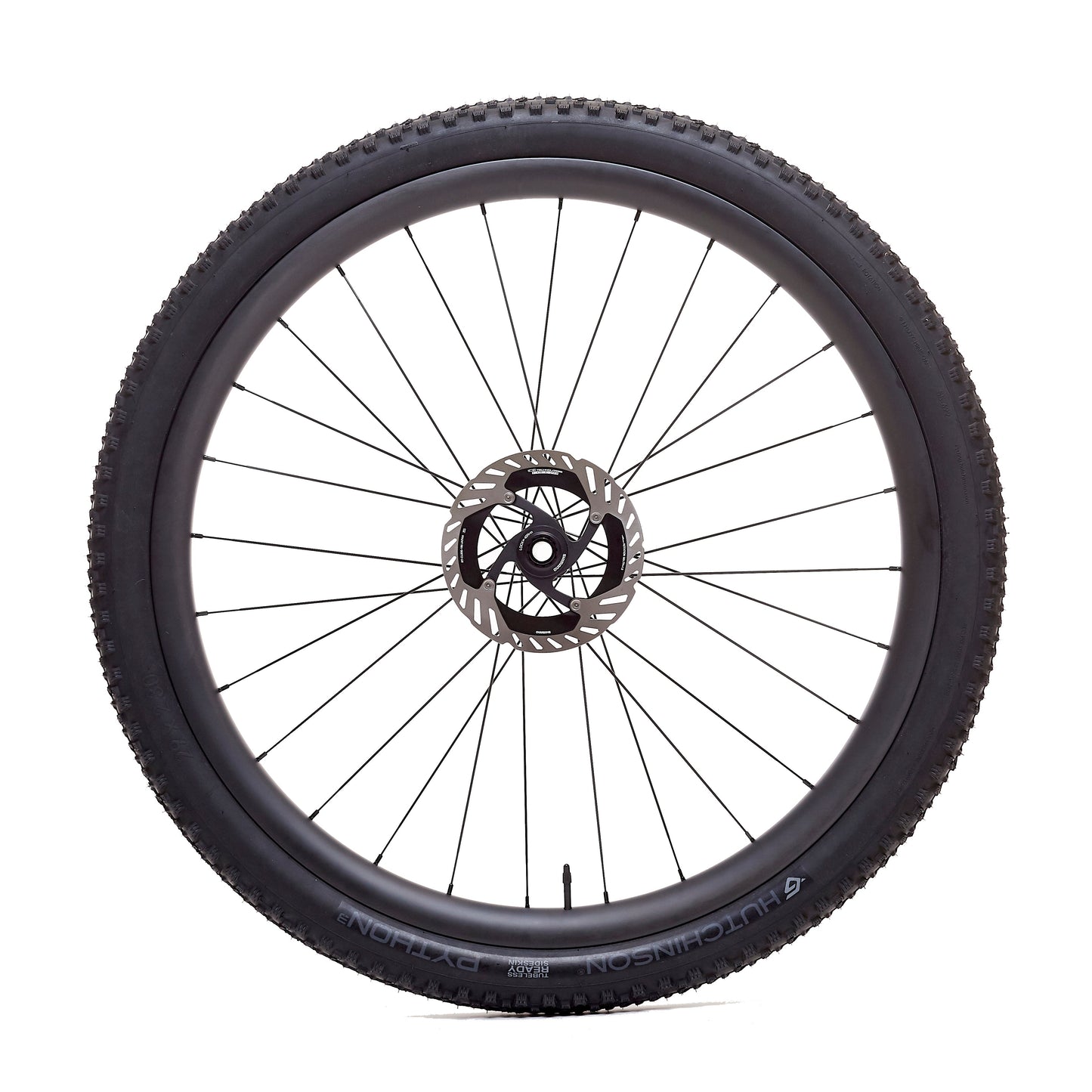 Rueda de carbono 30mm para enduro vista frontal, diseño con agujeros asimétricos en la llanta que distribuyen mejor la tensión de los radios, mejorando la rigidez lateral y la estabilidad en las secciones más exigentes.