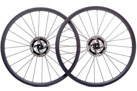 Par de ruedas de carbono 30mm para gravel, perfil aerodinámico, bujes Ratchet System y diseño Tubeless Ready, ideales para estabilidad y rendimiento en terrenos mixtos.