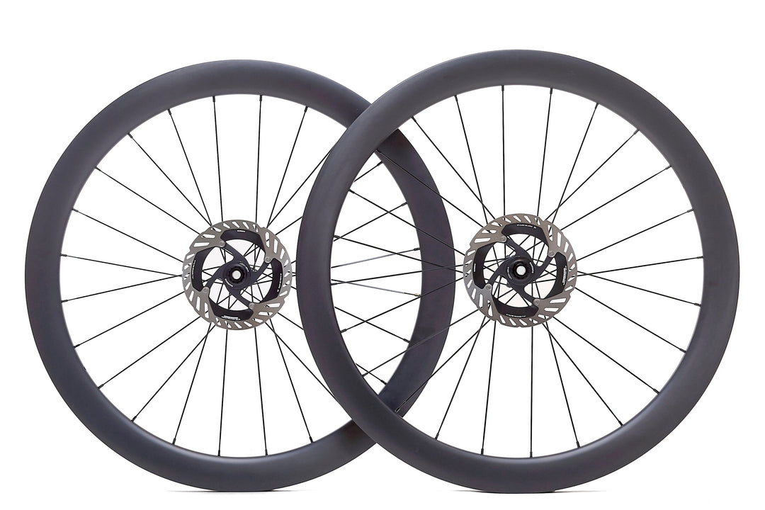 Par de ruedas de carbono 50mm para carretera con perfil aerodinámico, bujes Ratchet System y tecnología Tubeless Ready. Mejora la aerodinámica y la estabilidad en recorridos largos, ideales para reducir la resistencia al viento.