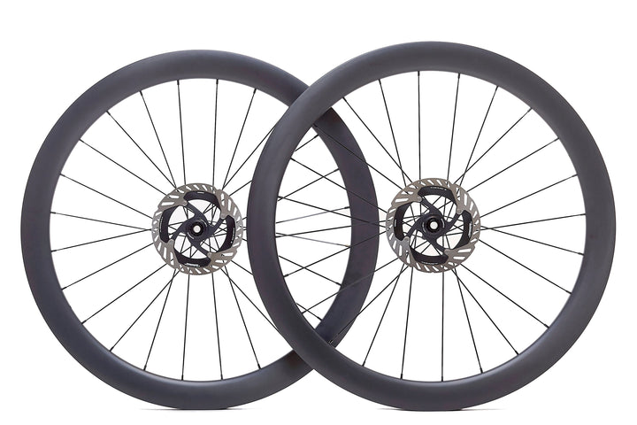 Par de ruedas de carbono 50mm para carretera con perfil aerodinámico, bujes Ratchet System y tecnología Tubeless Ready. Mejora la aerodinámica y la estabilidad en recorridos largos, ideales para reducir la resistencia al viento.