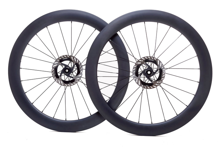Par de ruedas de carbono 60mm para carretera con perfil aerodinámico, bujes Ratchet System y tecnología Tubeless Ready. El diseño de 60mm mejora la aerodinámica y reduce la resistencia al viento, ideal para mejorar la velocidad y estabilidad en recorridos largos