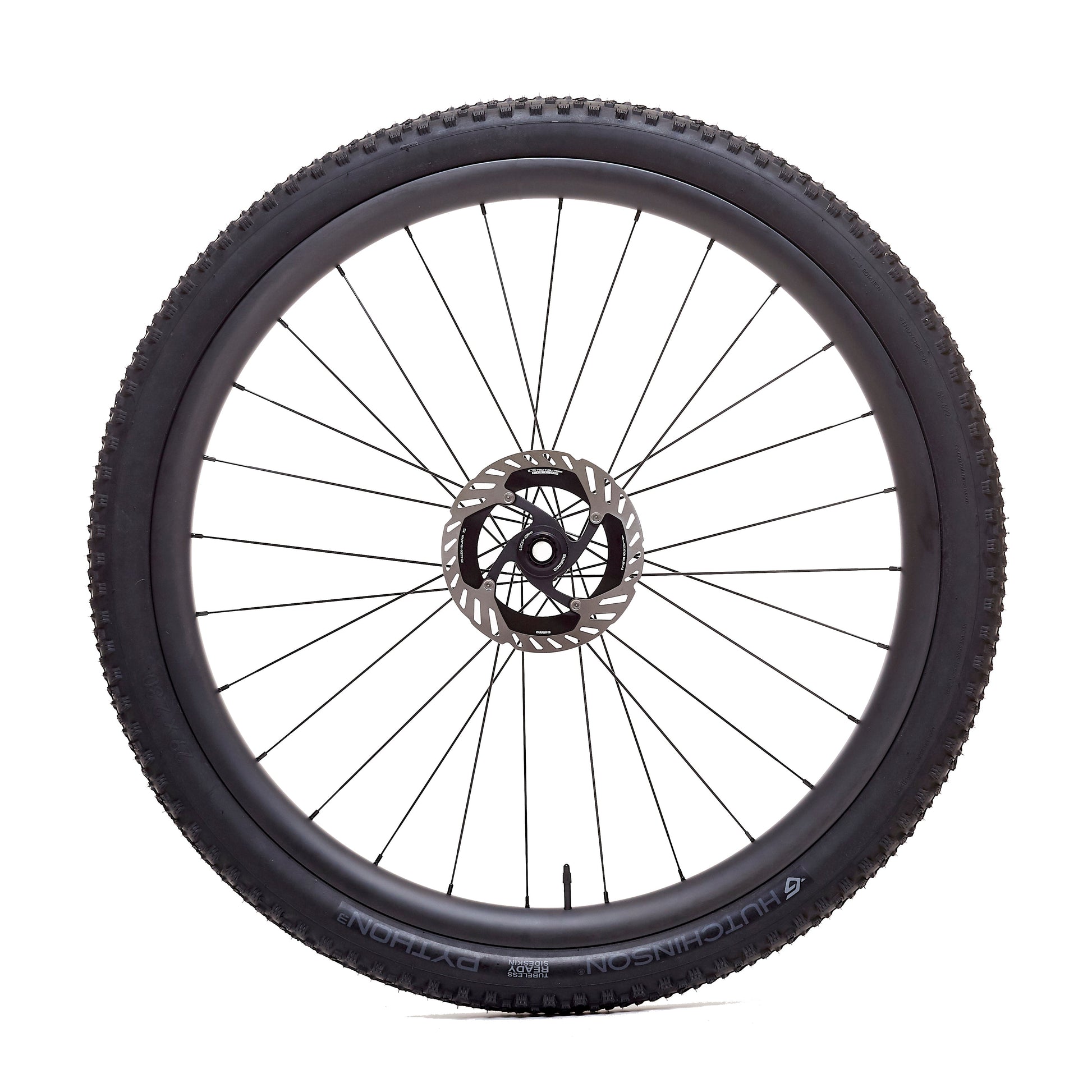 Rueda de carbono 30mm para enduro vista frontal, diseño con agujeros asimétricos en la llanta que distribuyen mejor la tensión de los radios, mejorando la rigidez lateral y la estabilidad en las secciones más exigentes.